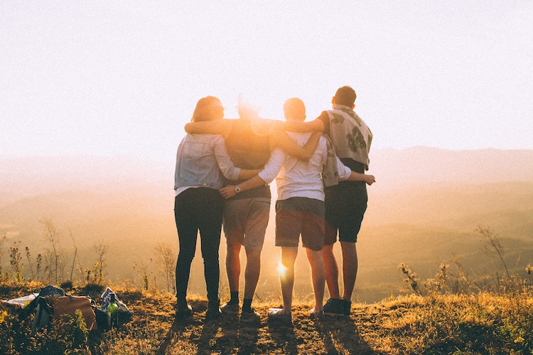 Four people huddling
together looking to the sunset.